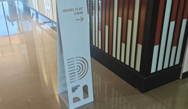 White directional signage stand inside the sales gallery pointing towards the 3 BHK Model Flat at Nambiar District 25
