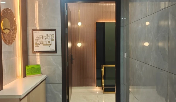 Entrance vestibule view of the 3 BHK model flat at Nambiar District 25, showcasing vertical slat wall paneling, hanging pendant lights, and a premium wooden door