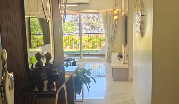 Interior view of the entrance hallway in the Nambiar District 25 4 BHK model flat, featuring polished marble flooring, decorative Buddha statues on a console, and a clear view into the sunlit living area