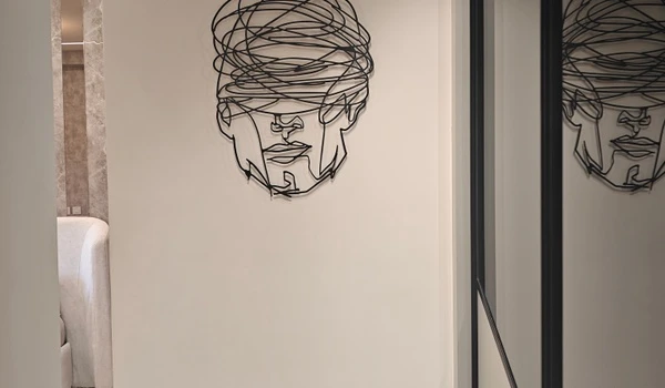 Close-up of a modern black wire face sculpture mounted on the hallway wall in the Nambiar District 25 4 BHK model flat
