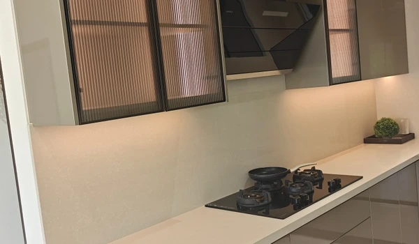 Close-up of the modern 4 BHK modular kitchen at Nambiar District 25, showcasing sleek fluted glass wall cabinets, integrated under-cabinet LED lighting, and a high-end built-in gas hob