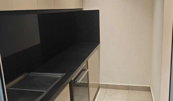 Kitchen utility area in the Nambiar District 25 4 BHK model flat featuring a black granite countertop, stainless steel sink, and beige cabinetry for additional storage