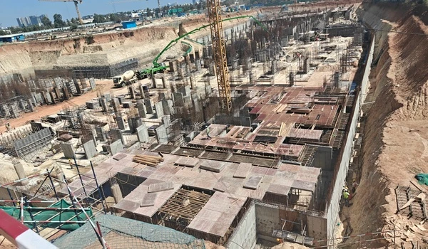 Overhead view of Nambiar District 25 construction site showing steel reinforcement grids and column starters at the basement level