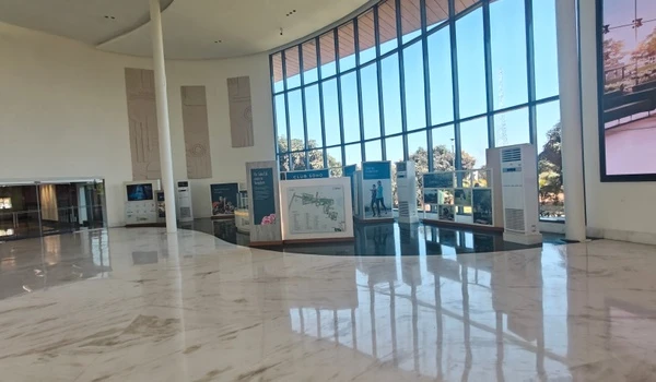 Interior view of Nambiar District 25 sales gallery featuring display boards for 'Club Soho', floor-to-ceiling glass windows, and polished marble flooring