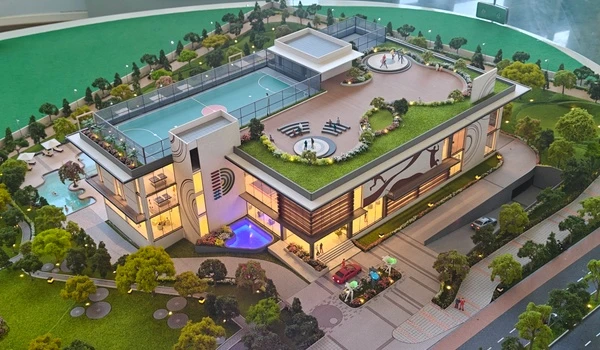 Side elevation of Nambiar District 25 clubhouse model showing the main entrance ramp, drop-off zone, and rooftop amenities