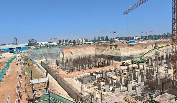 Panoramic view of Nambiar District 25 construction site highlighting the deep excavation pit, retaining wall stabilization, and foundation pillars