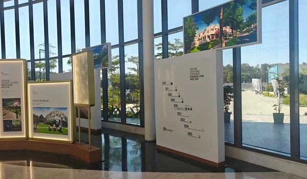 Interior display board at Nambiar District 25 marketing office showcasing the developer's project timeline and history from 2009 to 2025