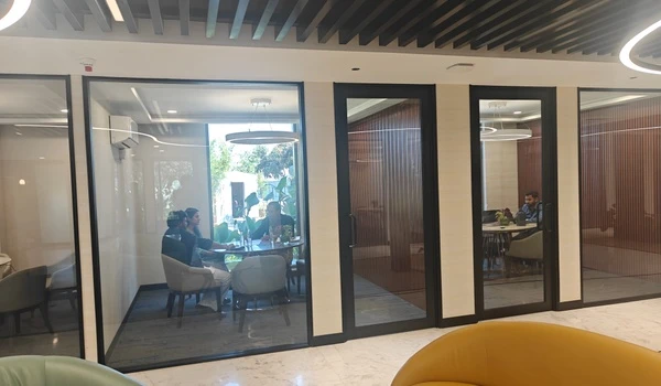 Interior view of Nambiar District 25 sales gallery showing occupied glass-enclosed meeting rooms designed for private client discussions