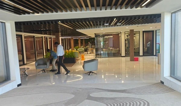 Spacious customer lounge area at Nambiar District 25 marketing office featuring modern interior design, glass meeting rooms, and comfortable seating arrangements