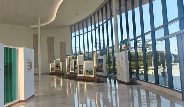 Interior view of Nambiar District 25 marketing office featuring floor-to-ceiling glass windows, illuminated project display boards, and polished marble flooring