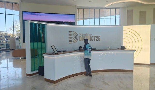 Interior view of Nambiar District 25 marketing office featuring a modern curved reception desk, gold branding on the wall, and polished marble flooring