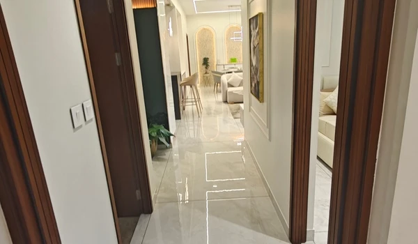 View of the polished marble hallway at Nambiar District 25 model flat, leading into the open-concept living and dining area with luxury furniture and ambient lighting