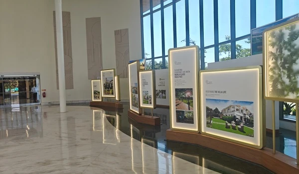 Row of illuminated display boards at Nambiar District 25 marketing office highlighting world-class facilities and villa lifestyle features
