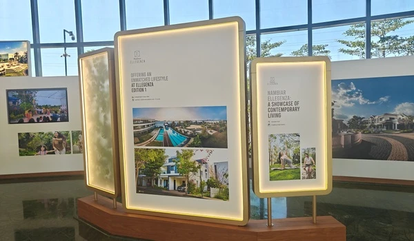 Illuminated display stands inside the marketing office showcasing Nambiar Ellegenza with images of villas, pools, and contemporary lifestyle